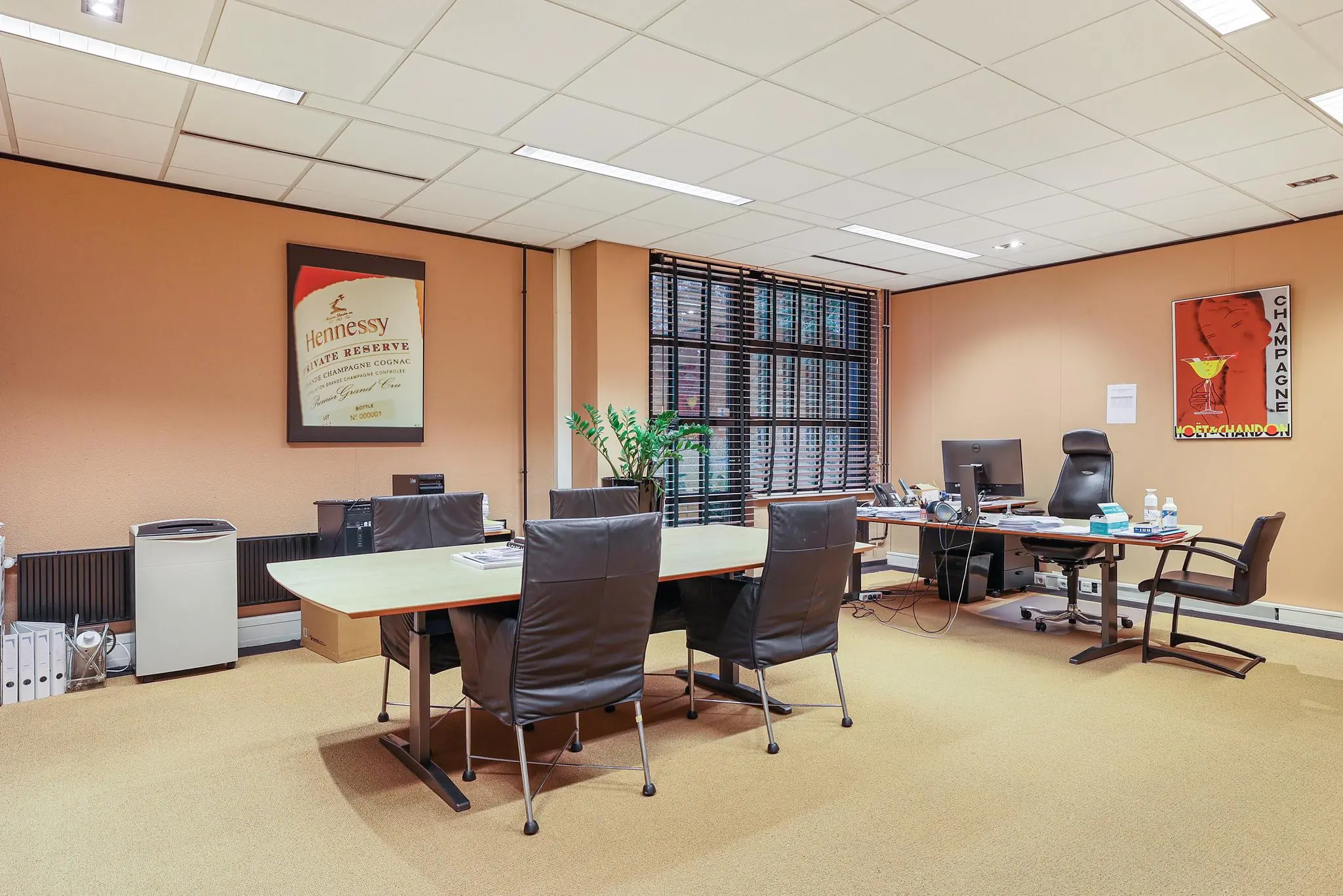 Modern kantoor met vergadertafel, werkplek en opvallende Hennessy- en Champagne-posters aan de muren aan de Oude Utrechtseweg.